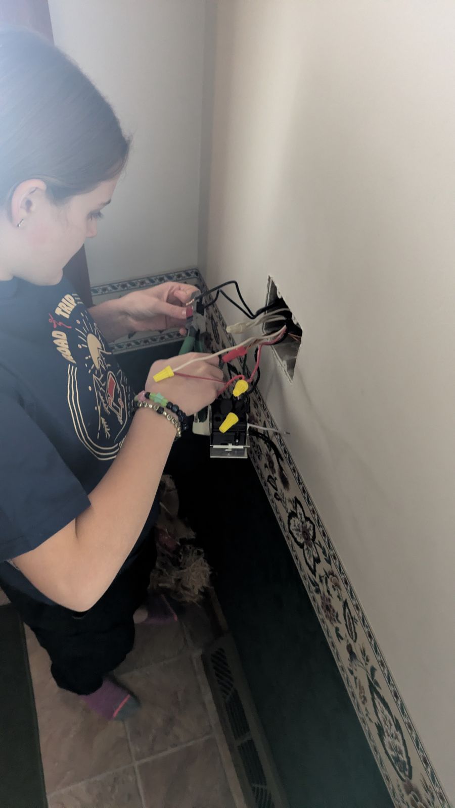 Electrician wiring a receptacle in a device box during a Benrishi Electrical service visit