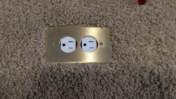 Brass floor outlet set flush in a carpeted floor