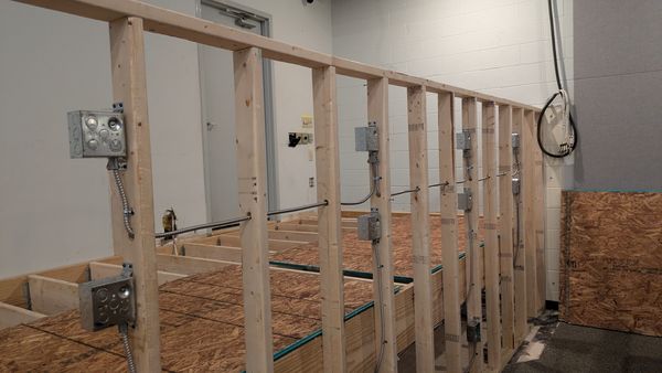 Device boxes and conduit roughed in along a framed commercial wall