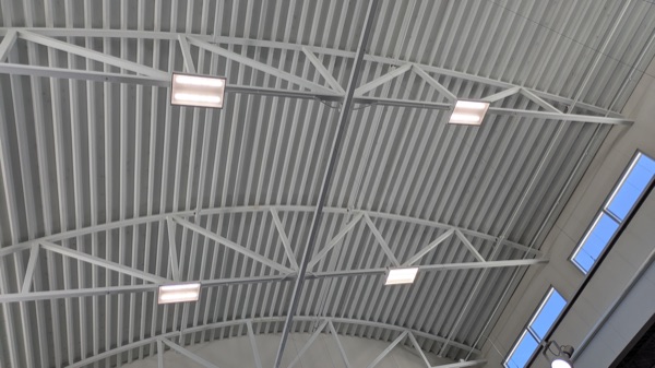 High-bay light fixtures mounted to a commercial steel truss ceiling