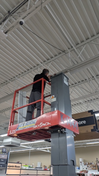Technician on a Skyjack lift servicing ceiling lighting in a store