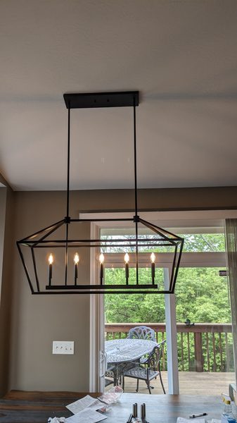 Rectangular black lantern chandelier over a dining area