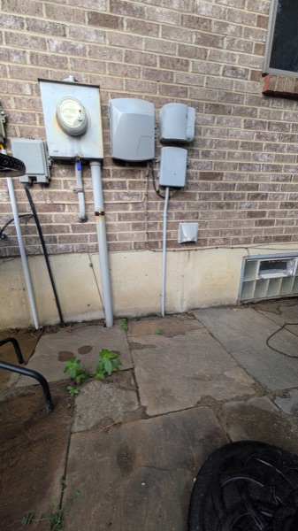 Exterior electric meter, disconnect, and conduit on a brick home