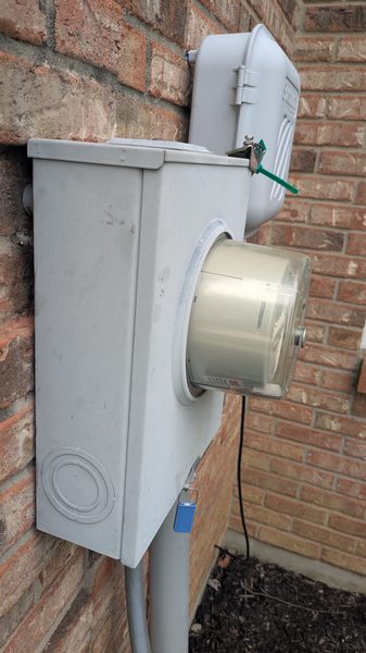 Exterior meter socket and conduit mounted on a brick wall