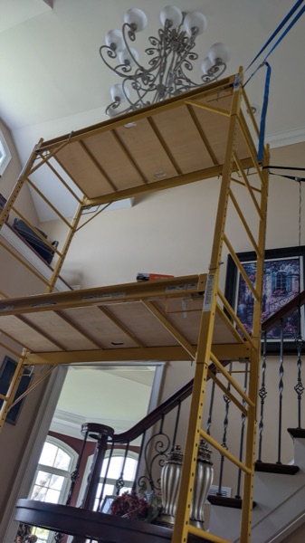 Scaffold tower set up to install a foyer chandelier in a high-ceiling home