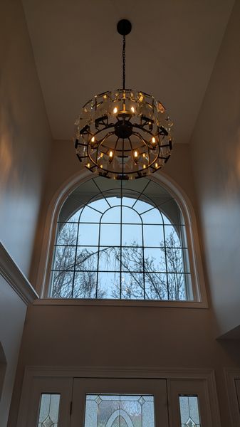 Crystal drum chandelier installed in a two-story foyer above an arched window