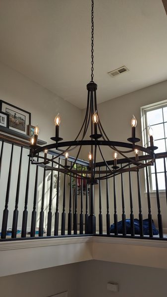 Black iron ring chandelier hung over a second-floor stair landing