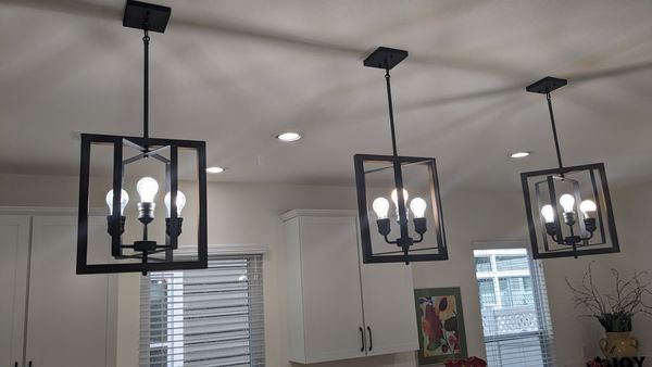 Three black cage pendant lights installed in a row over a kitchen