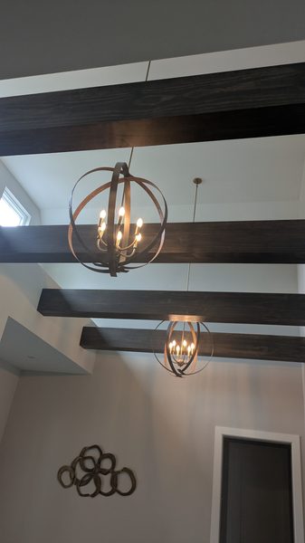 Orb chandelier and matching pendant hung between dark ceiling beams