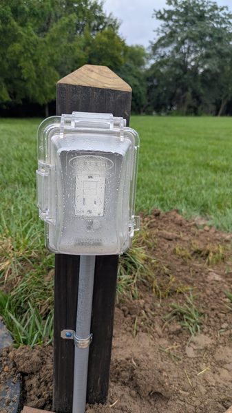 Outdoor outlet on a wood post with a weatherproof in-use cover