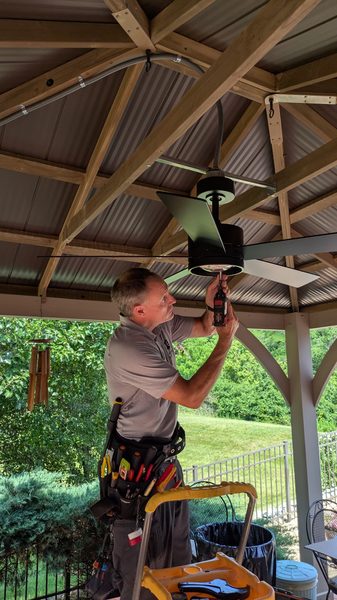 Ceiling fan being installed under an outdoor pavilion