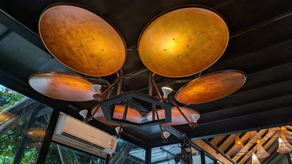 Custom copper-disc chandelier installed in a restaurant dining area