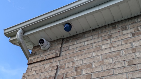Exterior security cameras mounted under the eave of a brick home