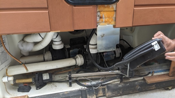 Open hot tub equipment bay showing pumps, plumbing, and wiring
