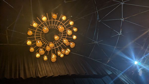 Circular cluster of woven pendant lights in a dimly lit event venue
