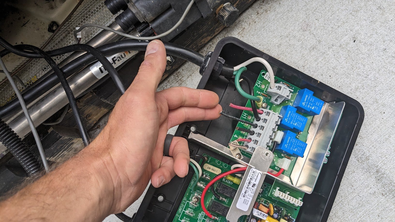 Jason landing conductors on a spa control-pack terminal block during a hot tub hookup — the kind of careful, code-correct termination work Benrishi Electrical is known for