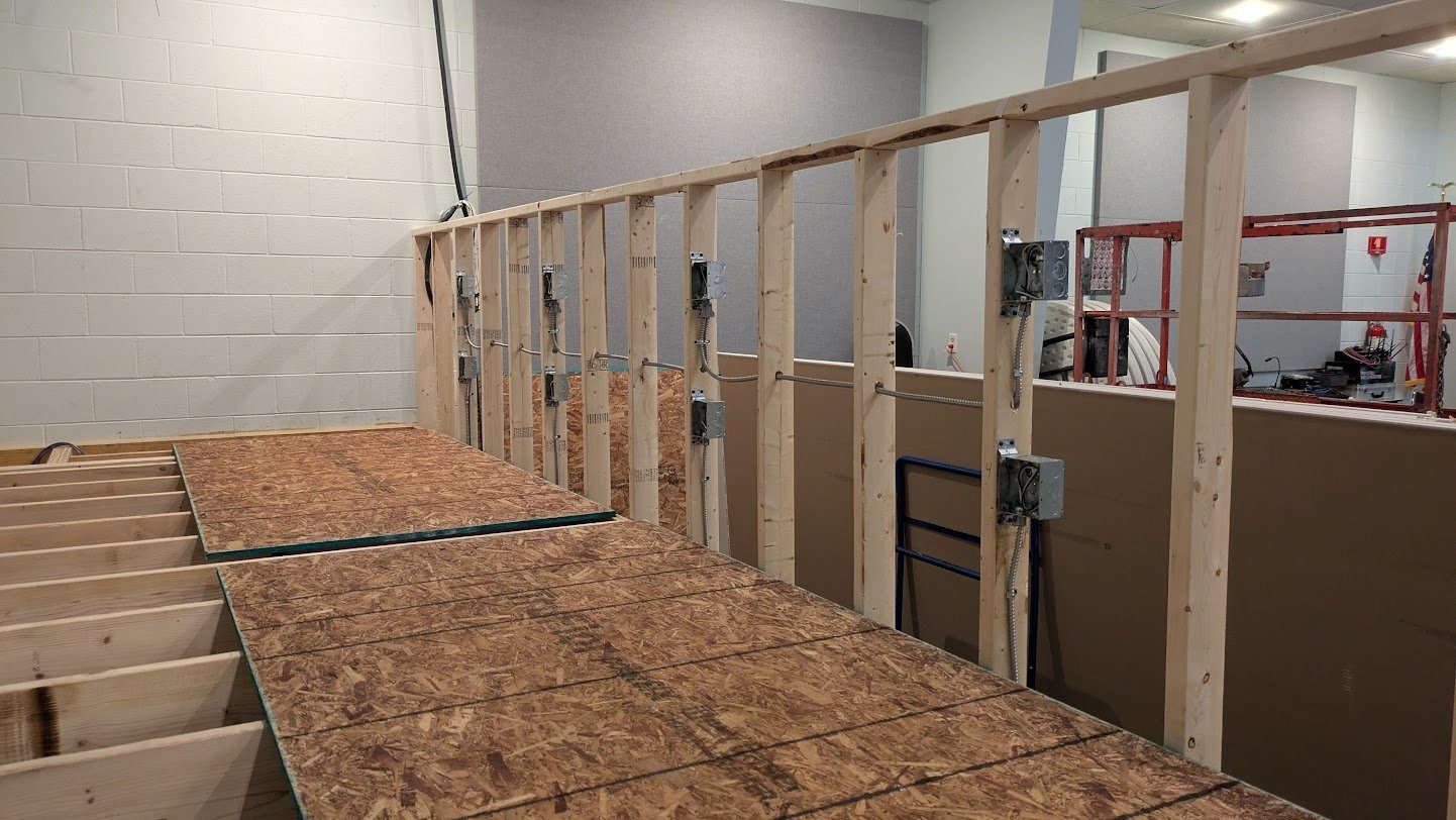 Commercial electrical rough-in with metal boxes and MC whips on a framed wall by Benrishi Electrical
